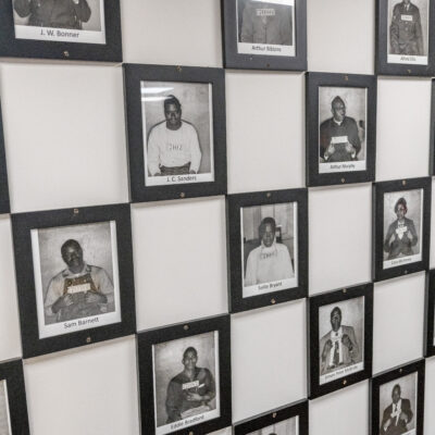 Framed mugshots of protestors who were arrested arranged in a grid on a wall