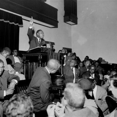The Rev. Martin Luther King, Jr. is shown speaking to an overflow crowd at a mass meeting at the Holt Street Baptist Church