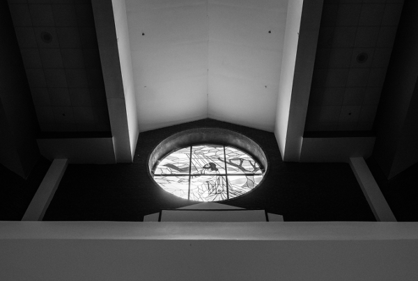 Black-and-white detail photo of Holt Street Memorial Baptist Church's vaulted ceiling, showing a round stained-glass window set beneath the peak of the sanctuary roof.